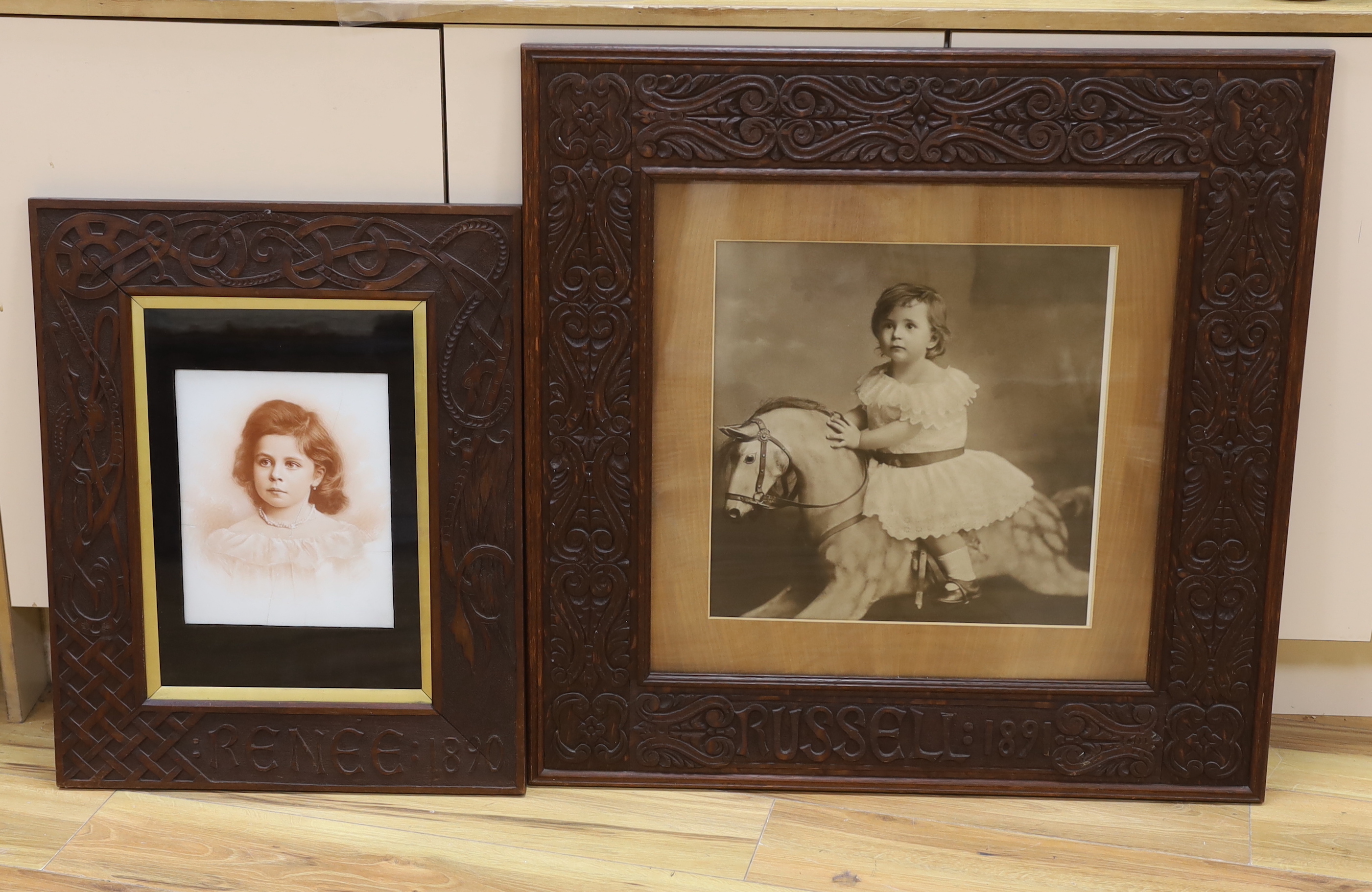 A large photographic print, Infant on rocking horse, housed in a carved frame ‘Russel, 1891’, and another similar framed sepia photograph, largest overall 79 x 79cm